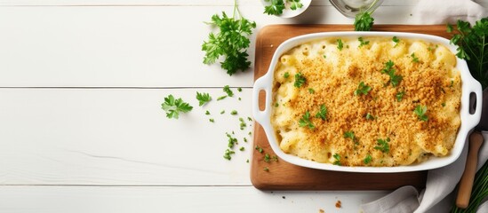 Close-up of casserole dish with wooden spoon and napkin, baked mac and cheese with breadcrumbs and parsley on white table