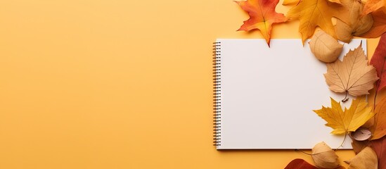 An open notepad with fall foliage and acorns on a golden background