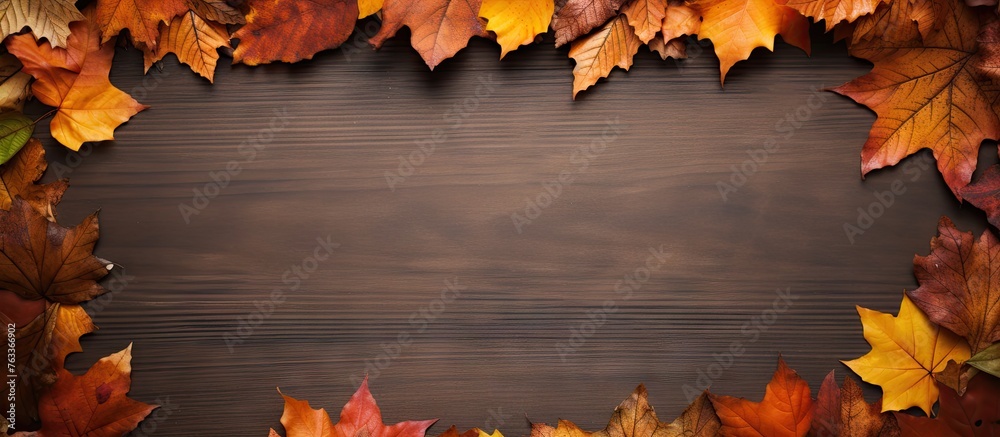 Poster autumn leaves border on wooden backdrop with space for text