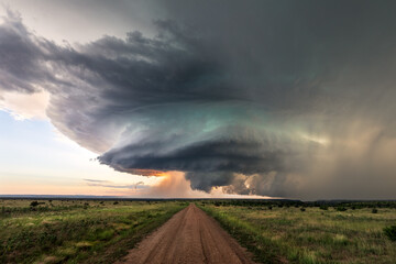 Dirt road leading to supercell storm clouds