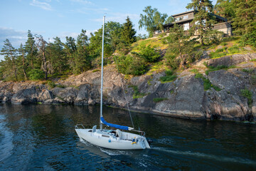 Stockholm Archipelago Sweden. Villa built on rocky formation in nature, vessel sails in water.