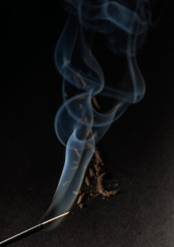 A head of incense stick with its human face shaped fume on a black background for graphic and web design use