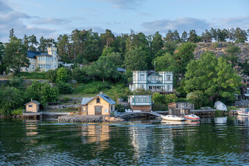 Stockholm Sweden Archipelago. Seafront villa, fishing hut, reflection in water, cloudy sky.
