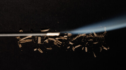 Ashes of a burning incense stick and its fume on the black textured background for graphic and web...