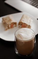 coffee on the desktop near the laptop . lunch at work