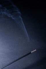 A closeup of incense stick and whirlwind fume on the black textured background for graphic and web...