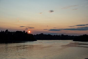 Naklejka premium Sunset over Archipelago, Stockholm Sweden. Sunbeam colors sea water. Silhouette of nature, ship.