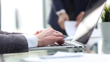 A businessman in the office is working at a desk with a laptop