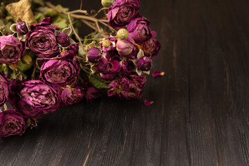 Bouquet of dry roses close-up on a wooden background.