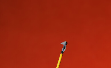 A closeup of a stick of an finished incense stick on the red background for graphic and web design use