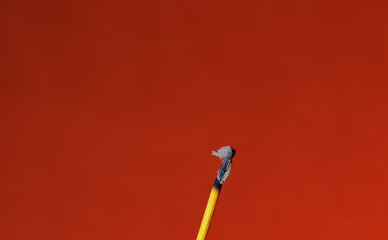 A closeup of a stick of an finished incense stick on the red background for graphic and web design use