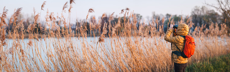 Bird watching at lake. Ornithologist with binoculars observe wildlife avian animals in natural...