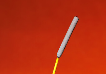 A closeup of a finished incense stick on the red background for graphic and web design use