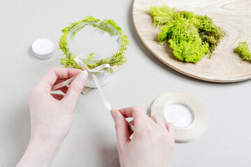 Florist at work: woman shows how to make simple Easter candle holder using a random glass and moss. Step by step, tutorial.