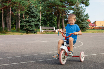 A little boy riding a tricycle on a road in the play ground
