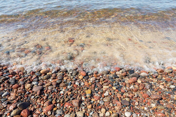The shore of the Baltic Sea close up. The sea wave smooths round sea pebbles