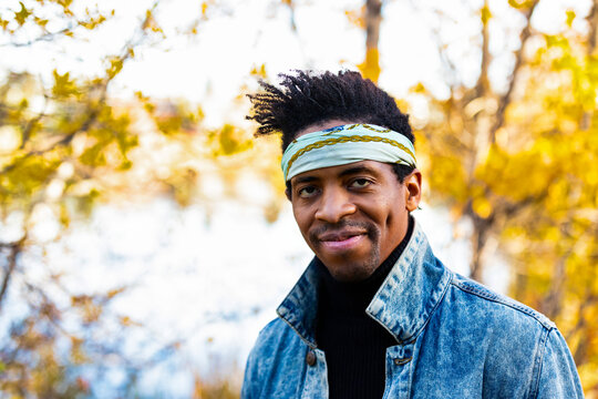 Close-up portrait of a handsome man wearing a bandanna headband, looking at the camera while in a city park in the Fall; Edmonton, Alberta, Canada