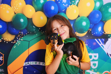 Menina com filhote de duchshund vestidas de brasil, bandeira do brasil, copa do mundo de futebol 