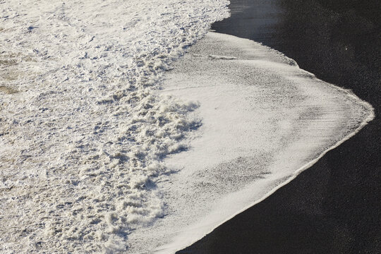 Textures of surf washing onto a black sand beach in Southern Iceland, on Dyrholaey Island near Vik; Dyrholaey Island, Iceland