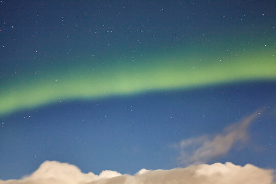 Northern lights in a blue sky filled with stars and a cloud formation, over Hellnar, Snaefellsnes peninsula, west coast of Iceland; Iceland