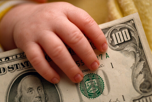 Baby's hand holding an American $100 bill; Mystic, Connecticut, United States of America