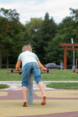 Back view of boy on a spin type swing with bare feet, in park