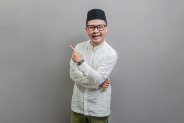 Asian Muslim man standing looking camera and pointing finger to right empty space