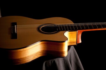 Fototapeta premium Classical Spanish flamenco guitar close up, dramatically lit isolated on black background with copy space.