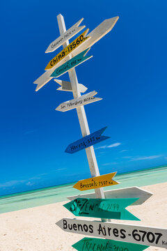 Signpost on a tropical white sand beach showing distance to countries around the world from Cuba in the Caribbean Sea; Cayo Guillermo, Cuba