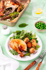 Baked chicken with baby potatoes and salad on a green background.