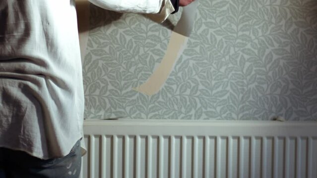 Hand stripping wallpaper from home internal wall close up