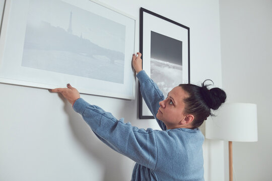 Woman hanging pictures on the wall and cleaning, remodeling apar