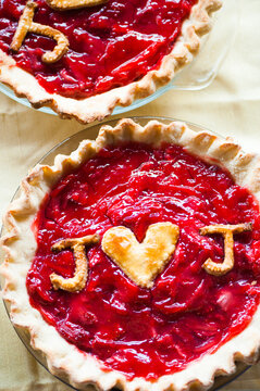 Two homemade fruit pies, one with a heart and initials baked in dough on top