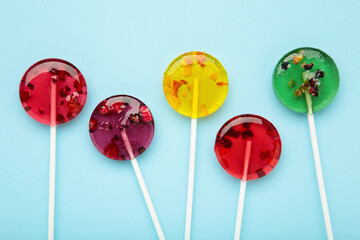 Colorful sweet lollipops with berries on blue background.