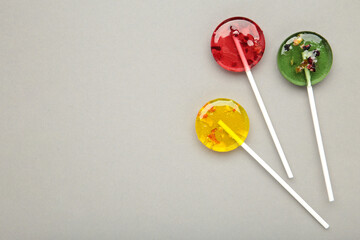 Colorful sweet lollipops with berries on grey background. Space for text