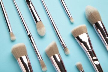 Set of makeup brushes on blue background.