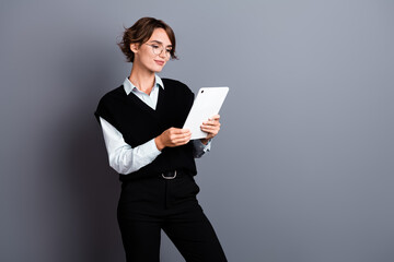 Photo of stunning confident lady wear stylish clothes reading report modern ipad gadget empty space isolated on gray color background