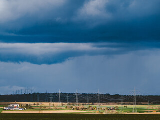 Strommasten einer Überlandleitung und dunkler Wolkenhimmel