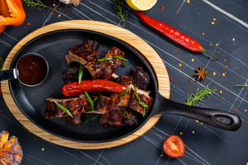 Grilled pork ribs on a wooden cutting board on a brown background