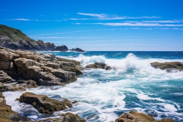 Fototapeta na wymiar Rocky coast under a clear blue sky background with crashing waves