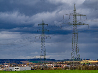 Strommasten einer Überlandleitung und dunkler Wolkenhimmel