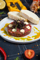 Veal tartar with wholemeal bread and egg on a white plate