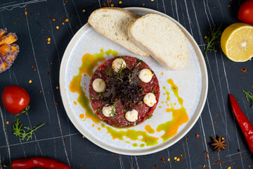 Veal tartar with wholemeal bread and egg on a white plate