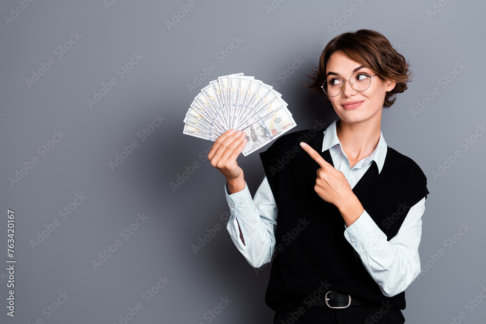 Wall mural Photo of stunning lovely lady banker wear trendy clothes showing dollars jackpot casino empty space isolated on gray color background