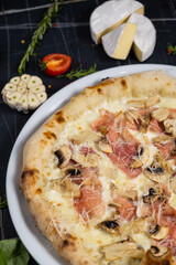 Bacon Pizza. Italian Carbonara Pizza with bacon and mozzarella cheese on black table, top view, close up.