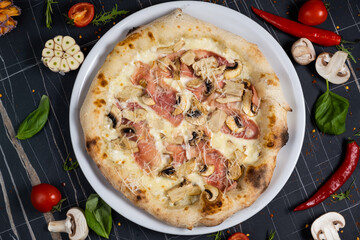 Bacon Pizza. Italian Carbonara Pizza with bacon and mozzarella cheese on black table, top view, close up.