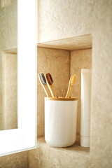 Natural bamboo toothbrushes in a glass in the bathroom.