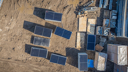 View from above on the construction site of photovoltaic park with stacked solar modules with a red crossed-out symbol indicating that they are damaged and other components. - obrazy, fototapety, plakaty