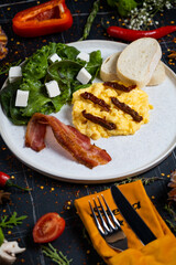 Breakfast with scrambled eggs, bacon and vegetable salad