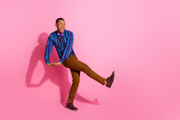 Fototapeta na wymiar Full length photo of positive funky guy wear striped shirt dancing disco empty space isolated pink color background